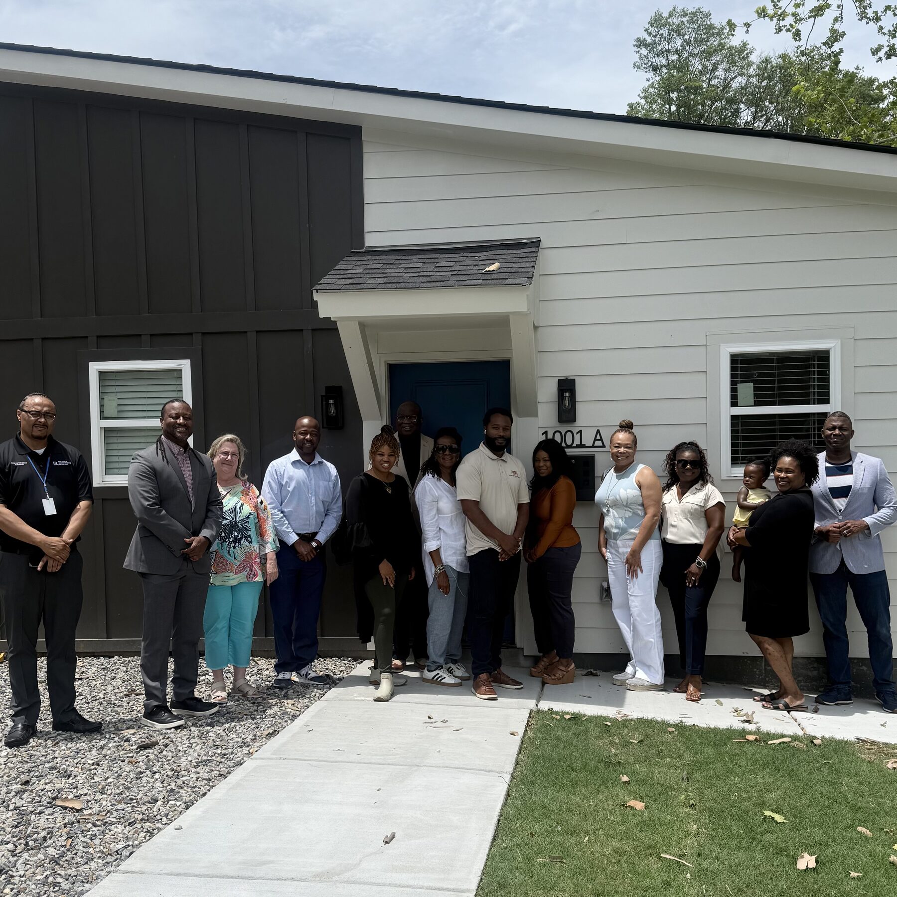 Natalie James with community partners and a family outside a newly built home in Little Rock
